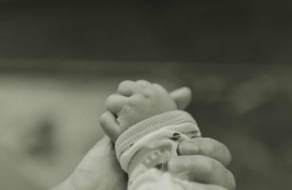 La main de Bébé sert le doigt de sa maman.