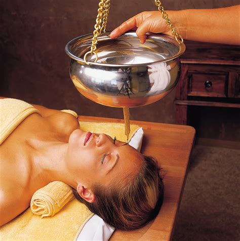 une femme reçoit un massage abhyanga, de l'huile chaude coule sur son visage